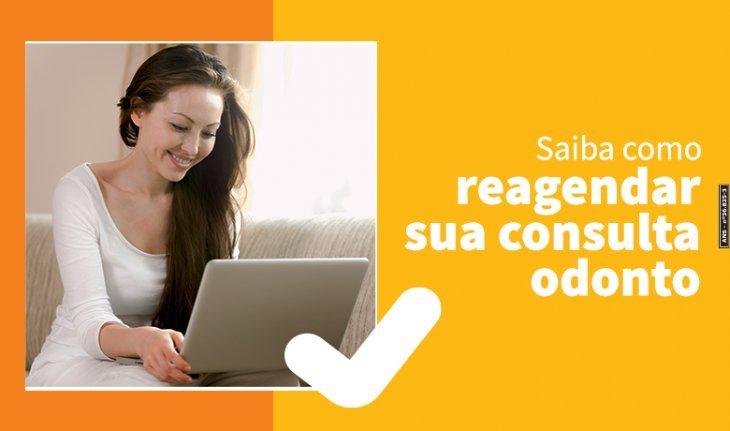 Imagem de uma mulher usando um notebook e a frase saiba como reagenda sua consulta odonto