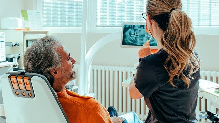 Imagem de dentista mostrando radiografia a paciente em consultório, destacando como incluir dependentes no seu plano odontológico