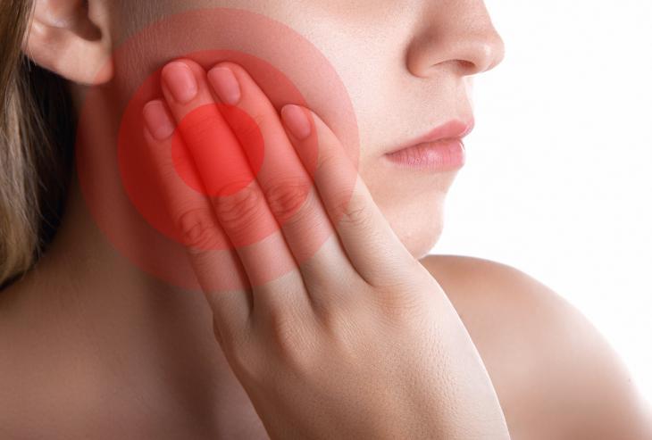 Imagem de uma jovem tocando o rosto com dor, destacando a região do siso com efeito vermelho, indicando desconforto dental