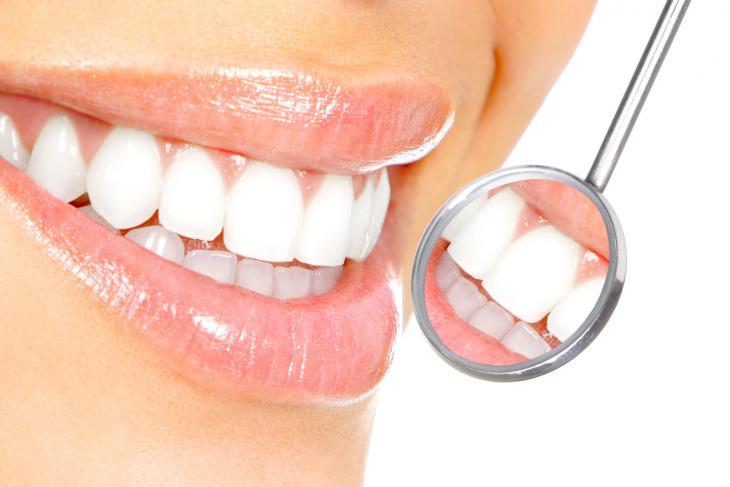 Imagem de uma mulher sorrindo, com o reflexo dos seus dentes, destacando a importância do cuidado com o esmalte dentário