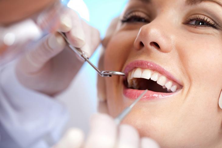 Imagem de uma mulher sorrindo em uma consulta odontológica, simbolizando os cuidados após a extração de dente
