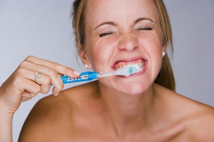 Imagem de uma mulher escovando os dentes
