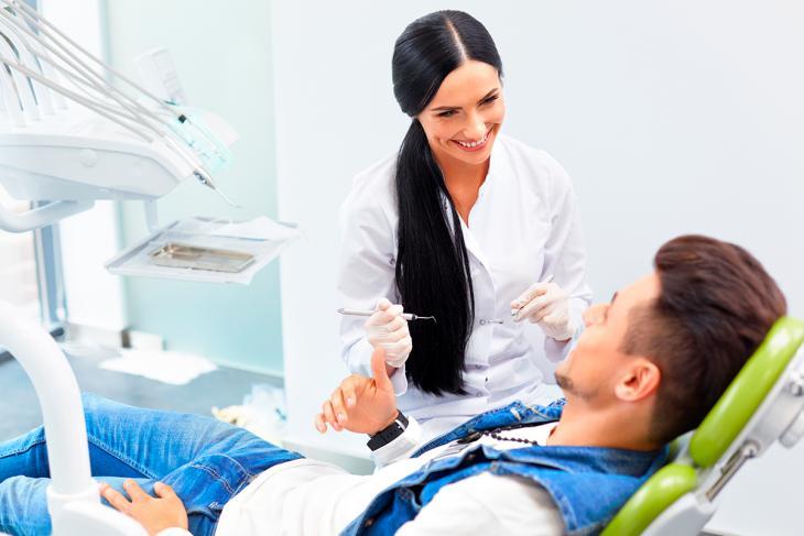 Imagem de uma dentista sorrindo enquanto atende paciente em consultório, destacando a importância do acompanhamento odontológico