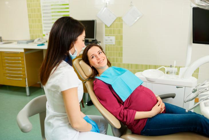 Imagem de uma gestante sorrindo enquanto recebe atendimento odontológico, destacando a importância da saúde bucal na gravidez