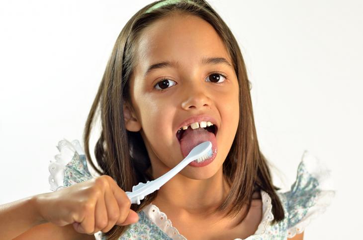 Imagem de uma jovem escovando a língua, destacando a importância da limpeza bucal para prevenir o mau hálito