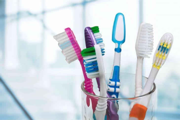 Imagem de um copo com algumas escovas de dente coloridas