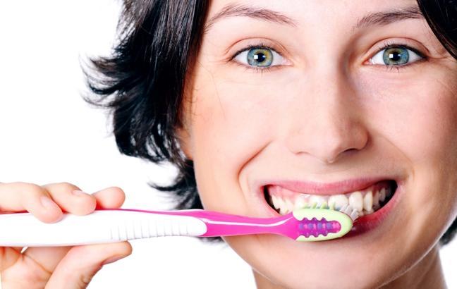 Close do rosto de uma mulher enquanto ela escova os dentes
