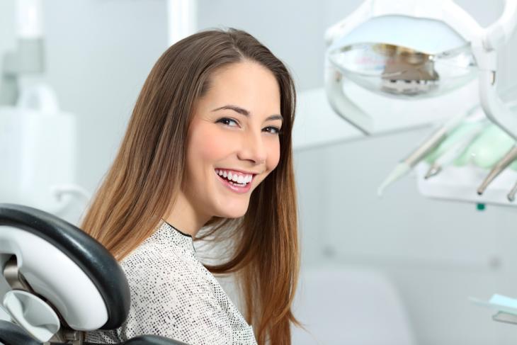 Imagem de uma mulher sorrindo em consultório odontológico, simbolizando dicas para não danificar os dentes