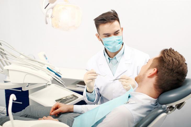 Imagem de dentista atendendo paciente em consultório, indicando cuidados com a saúde bucal evitando problemas como a endocardite