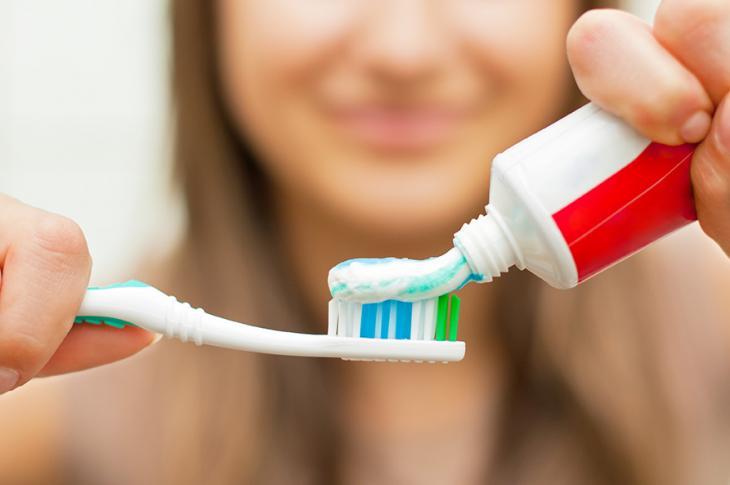 Pessoa aplicando creme dental em uma escova de dentes simbolizando que escolher uma escova adequada é essencial para saúde bucal