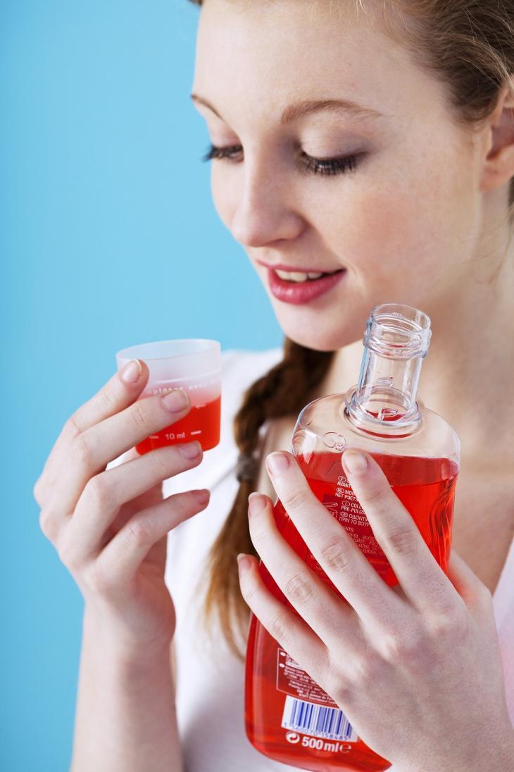 Imagem de uma mulher segurando um frasco de enxaguante bucal, simbolizando como utilizar o produto