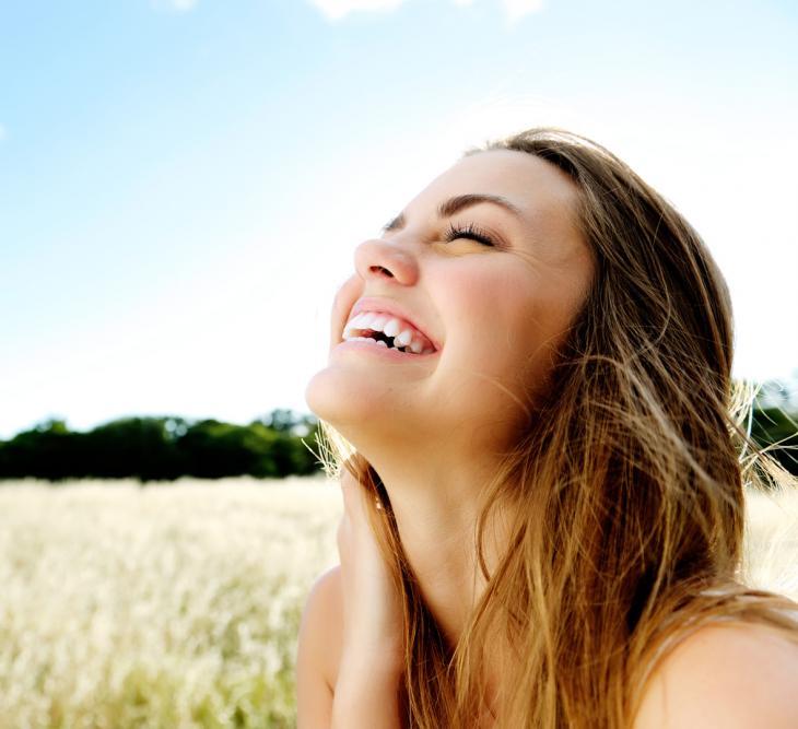 Imagem de uma mulher sorrindo em um campo