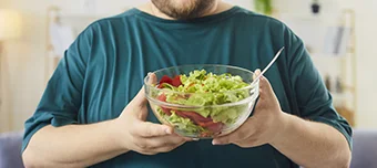 Homem com um pote de saladas na mão.